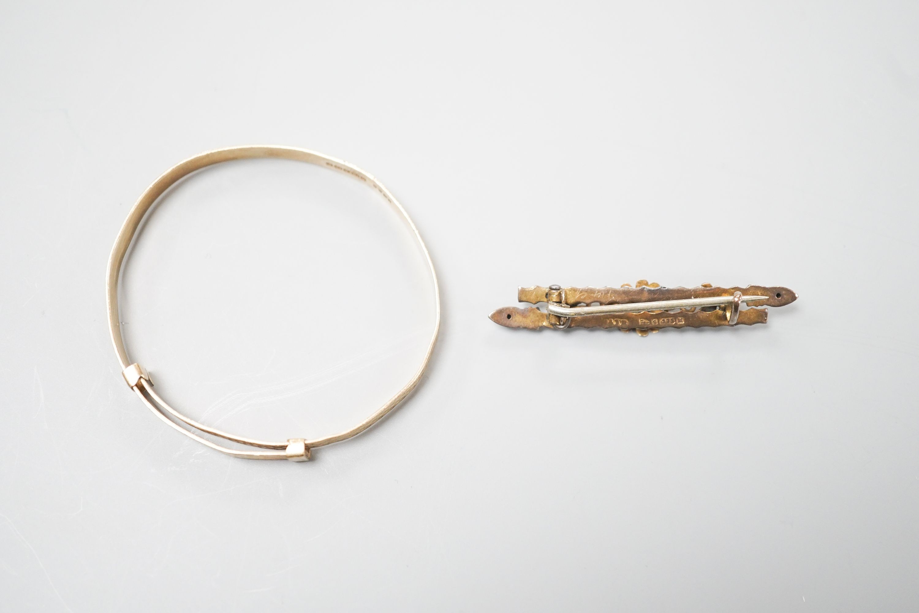 A modern 9ct gold child's bangle and a late Victorian 9ct gold bar brooch, gross 6.7 grams.